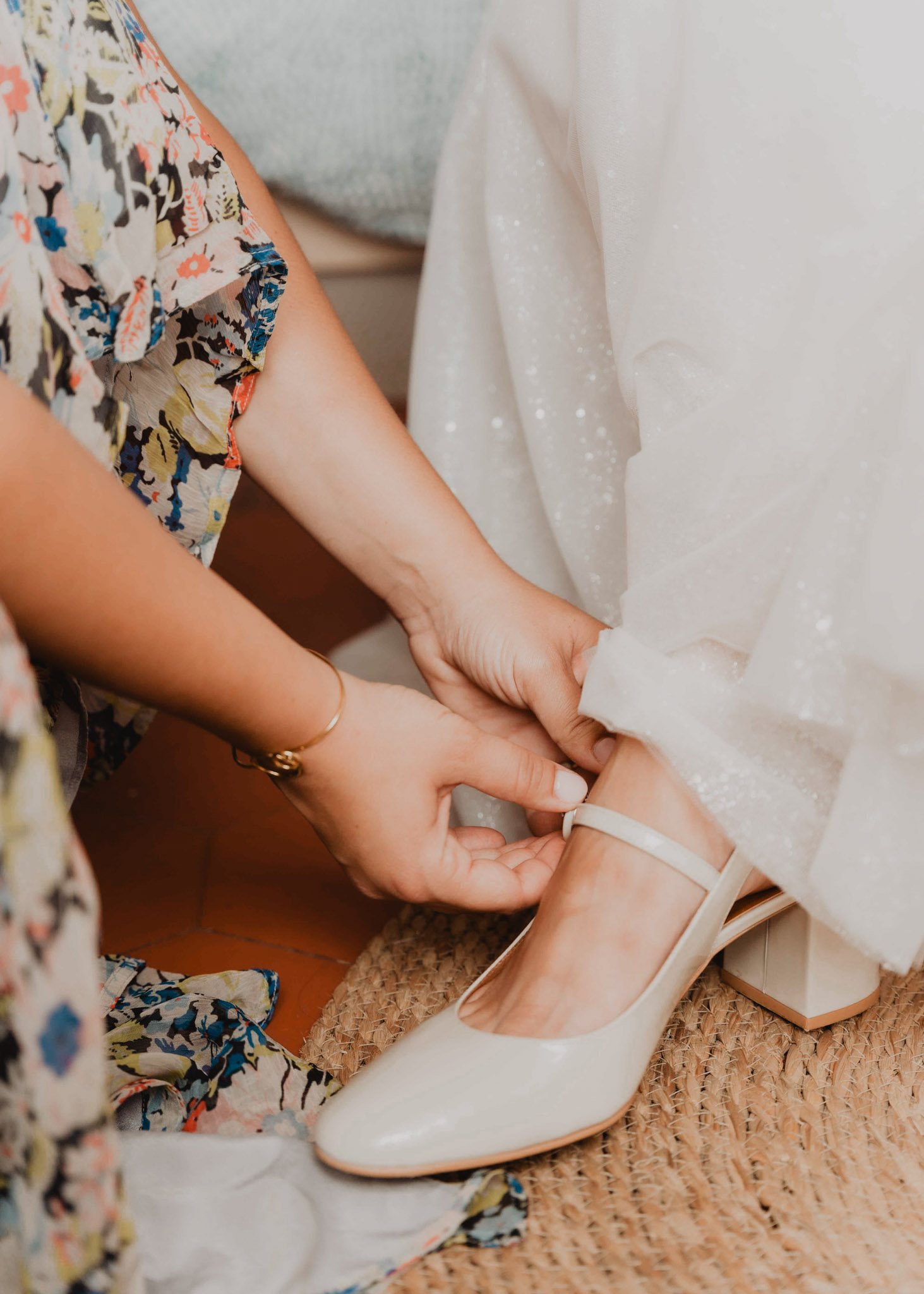 Unas manos ajustan el zapato de la novia.