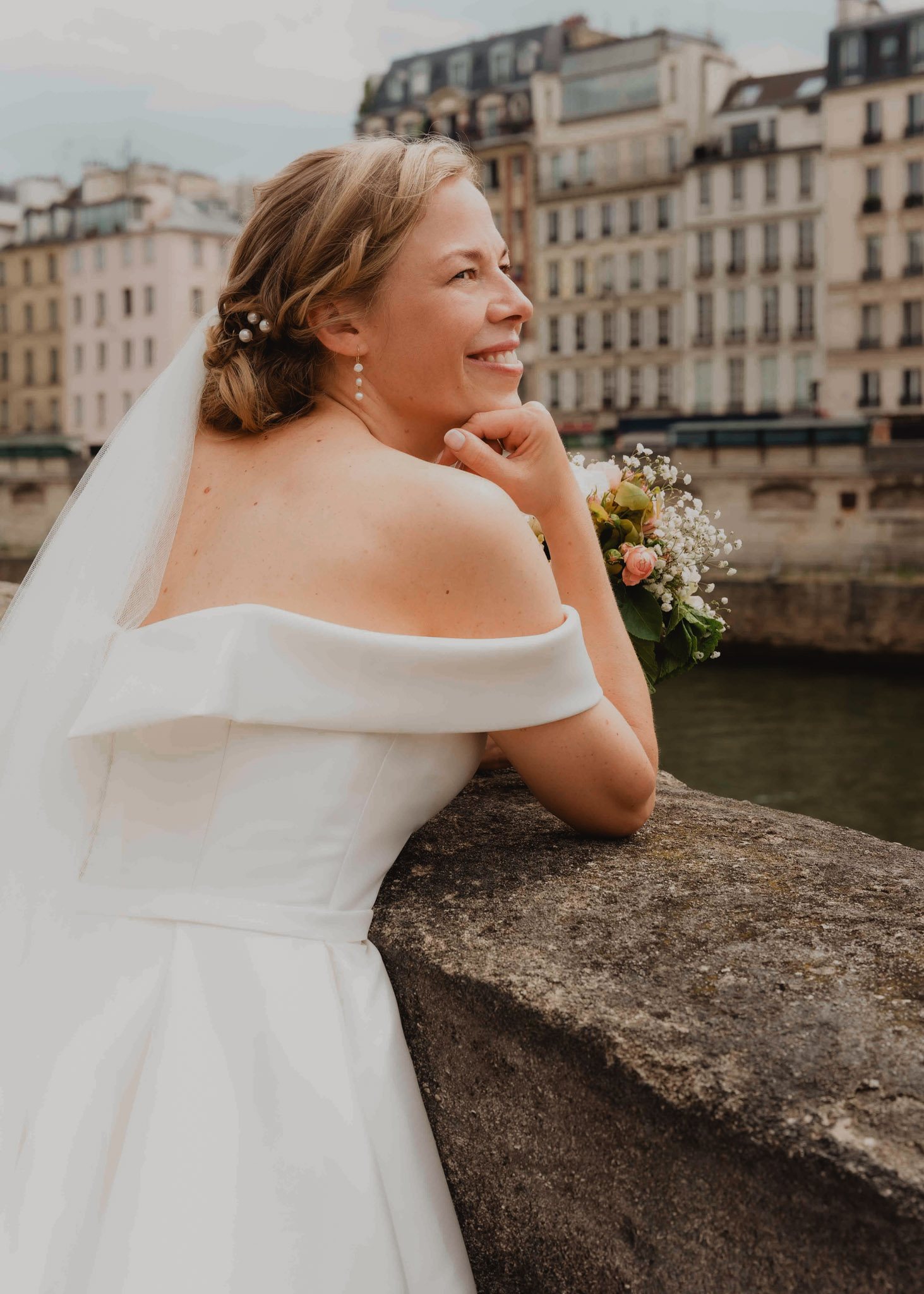 Una novia posa junto al río en París.