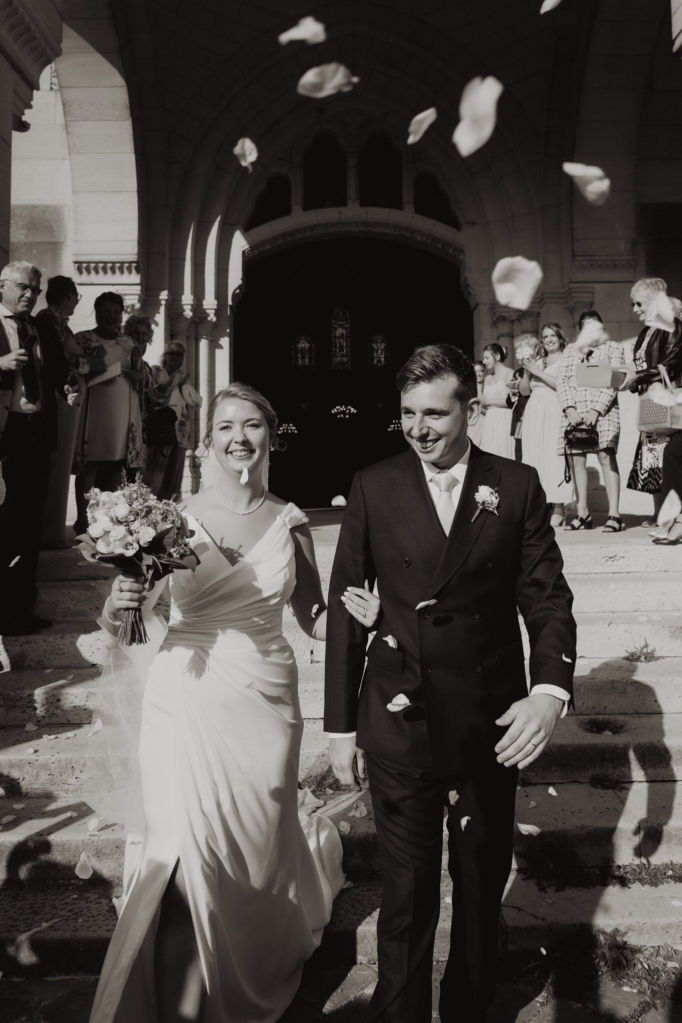Una pareja sale sonriente de la ceremonia en blanco y negro.