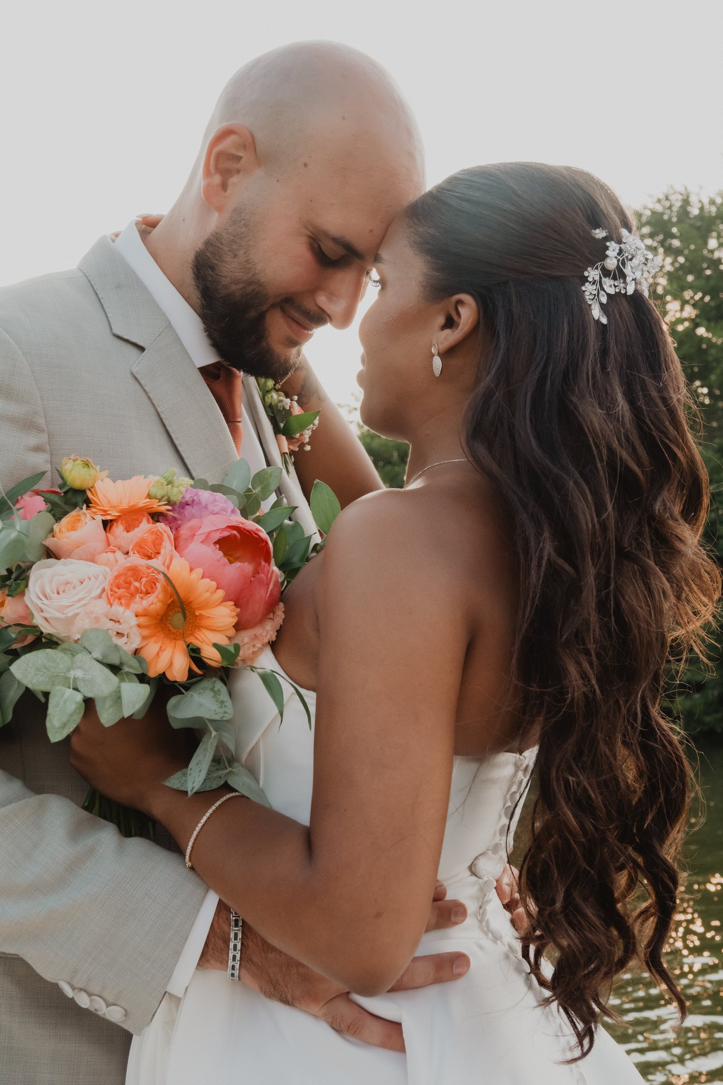 Una pareja se acerca entre un ramo de flores coral.