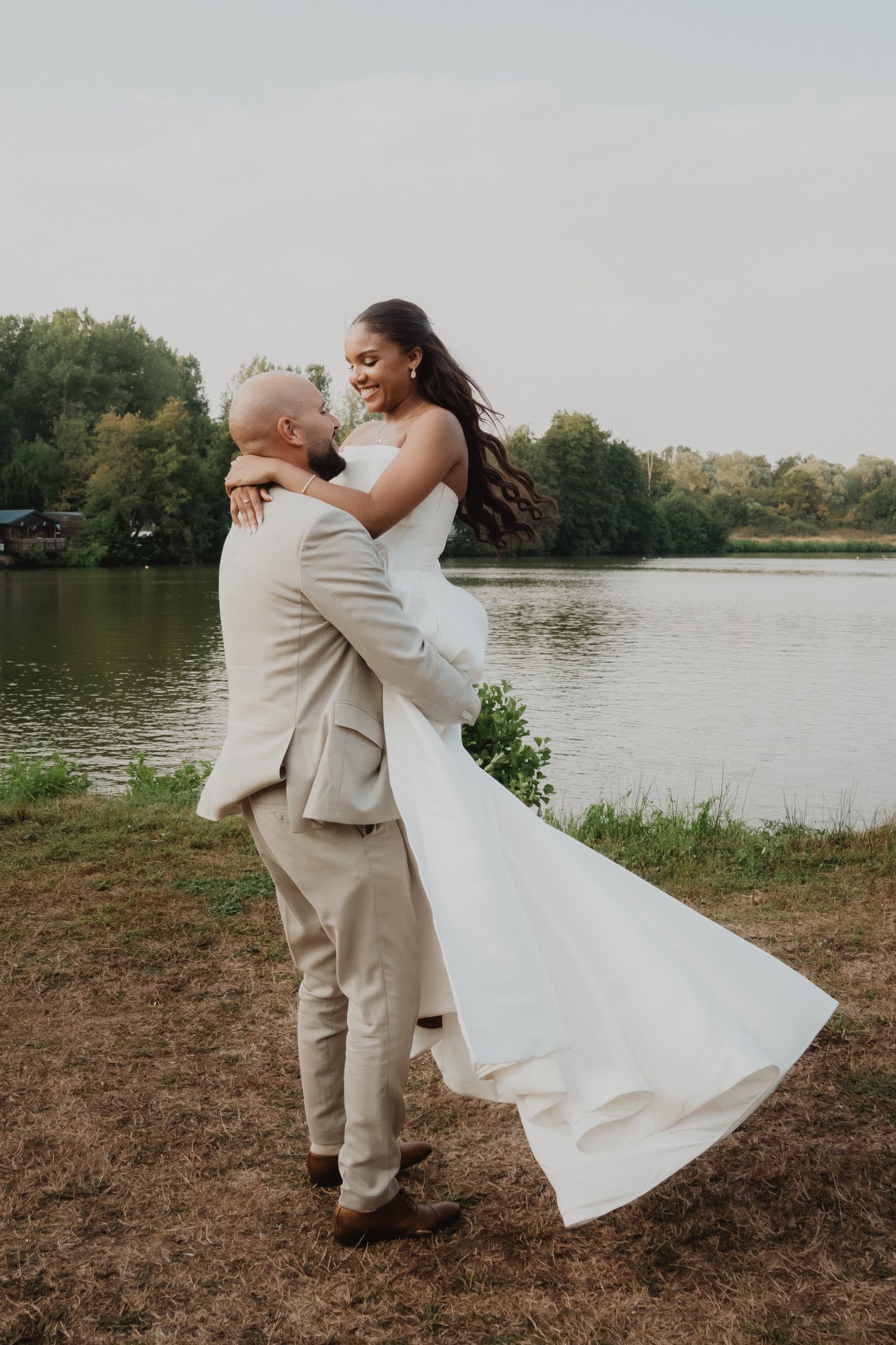 Un novio levanta a la novia junto al lago.