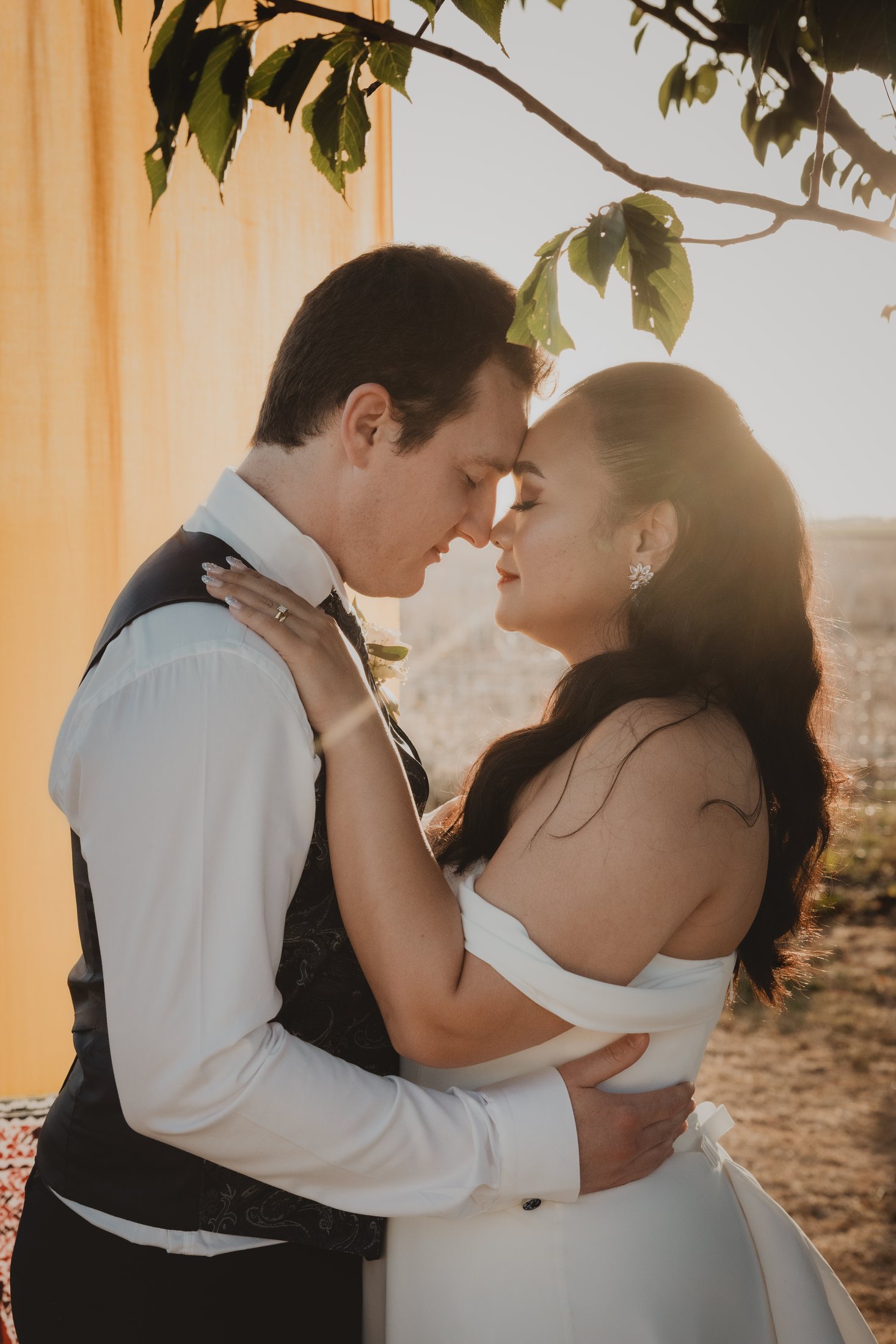 Una pareja se abraza a contraluz durante el atardecer.